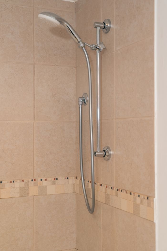 Elegant chrome showerhead and fixtures mounted on beige tiled shower wall.