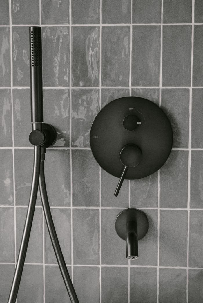Stylish matte black shower fixtures on modern tiled wall, capturing minimalist bathroom design.