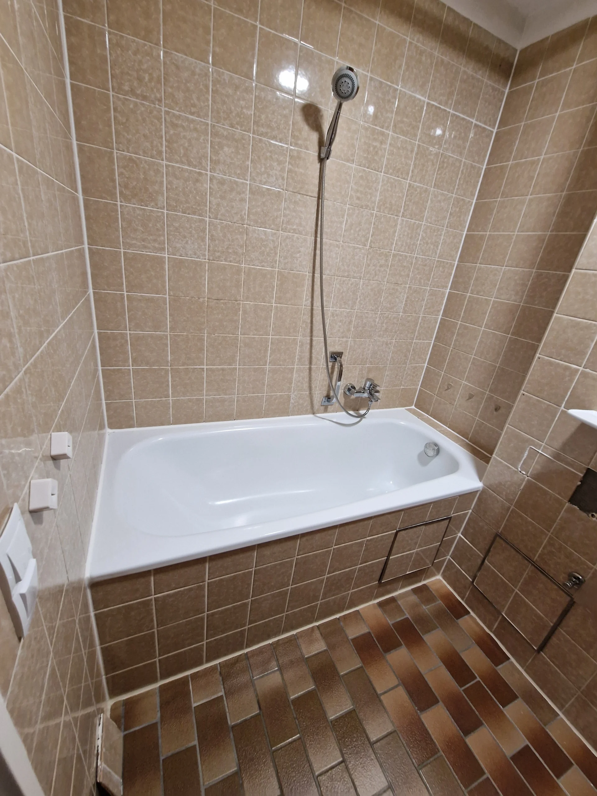 Altes Badezimmer vor der Sanierung mit beigefarbenen Fliesen.