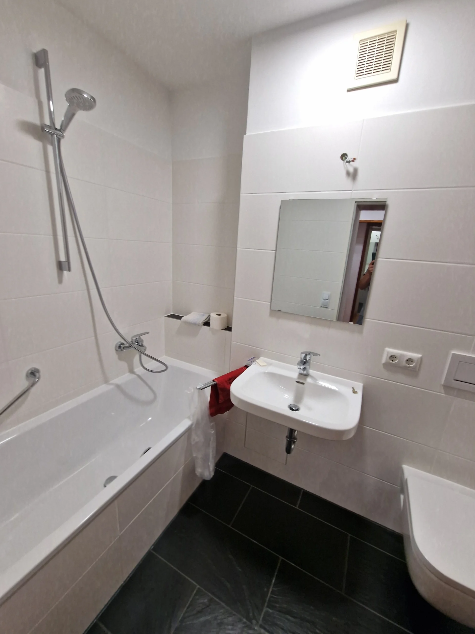 Modernes saniertes Badezimmer mit weißen Wandfliesen und schwarzem Boden.